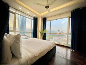 拉合尔Gold Crest Prime Heights Executive Apartments-DHA Lahore的一间卧室，里面有一张床和一扇大窗户。