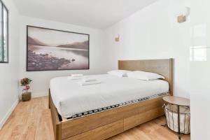 ein Schlafzimmer mit einem großen Bett mit weißer Bettwäsche in der Unterkunft Beau deux pieces au coeur de Neuilly in Neuilly-sur-Seine