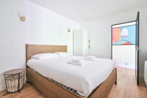 ein Schlafzimmer mit einem großen Bett mit weißer Bettwäsche in der Unterkunft Beau deux pieces au coeur de Neuilly in Neuilly-sur-Seine