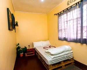 a small room with a bed with a window at Mango Hostel Arusha in Arusha