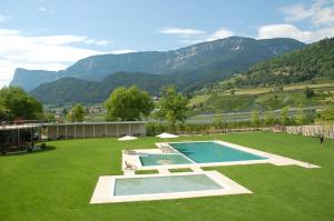 a swimming pool in the middle of a field with mountains at Ansitz Gurtenhof bei Meran, Apartments, Bett und bike Betrieb, eingezäunter Garten, Sauna, Eintritt ins Schwimmbad und Südtirol Pass in Tesimo