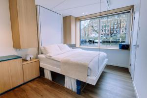 ein Schlafzimmer mit einem Bett und einem großen Fenster in der Unterkunft The Amsterdam Houseboat Family - de Jordaan Brand New Houseboat! in Amsterdam