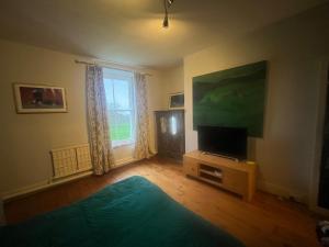 un soggiorno con TV a schermo piatto e ampia finestra di Castellmai a Caernarfon