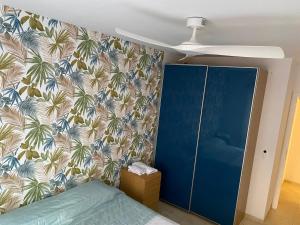 Casa Caletillas في كانديلاريا: غرفة نوم بسرير ازرق وورق جدران استوائي +صورة واحدة