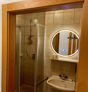 a bathroom with a shower and a sink and a mirror at Hotel-Gasthof Lammersdorf in Millstatt