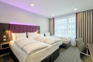 a hotel room with three beds and a purple headboard at Premier Inn Stuttgart Zuffenhausen in Stuttgart