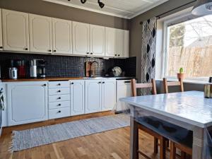 Lovely apartment, perfect for exploring Tjörn and Orust SE09153 في Varekil: مطبخ مع دواليب بيضاء وطاولة