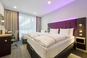 a hotel room with two beds and a purple headboard at Premier Inn Stuttgart Zuffenhausen in Stuttgart