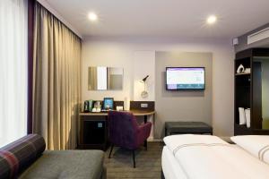 a hotel room with a bed and a desk with a computer at Premier Inn Stuttgart Zuffenhausen in Stuttgart