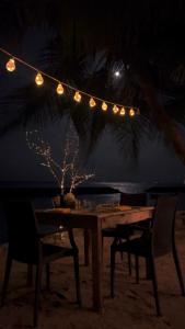 Nautical Nook Maldives في Kendhoo: طاولة على الشاطئ مع سلسلة من الأضواء