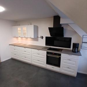 a kitchen with white cabinets and a black microwave at Eksklusiv stort boende i Fredrikshavn in Frederikshavn