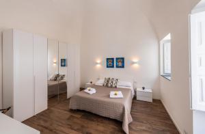 una camera da letto bianca con un letto e uno specchio di Terrazza in Centro - Casa Torres ad Acireale