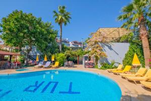 a swimming pool at a resort with chairs and palm trees at YENI DOGA HOTEL in Dalyan