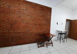 a brick wall with a wooden table and chairs against it at Pousada Villa in Piquete