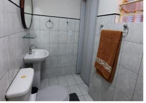 a white bathroom with a toilet and a sink at Pousada Villa in Piquete