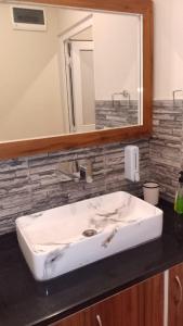 Un lavabo blanco en un baño con espejo. en Twin Oaks Kasauli Hills, en Kasauli