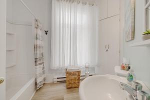 un bagno bianco con vasca e lavandino di Auberge du vieux pont a Saint-Raymond