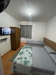 a bedroom with two beds and a flat screen tv at Hotel Colombo in São Lourenço