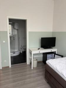 a bedroom with a bed and a desk with a television at Franken Motel in Fürth +11 photos