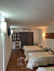 Una habitación de hotel con dos camas y una silla. en Toneles - Cafayate, en Cafayate