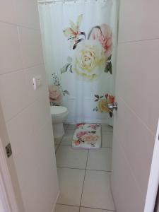 een badkamer met een toilet en bloemen aan de muur bij Serena Mar La Serena in La Serena