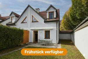 a white house with a table in the yard at DAS BURGENNEST, 5 Personen - 1 Preis, Bademantelgang zur Therme Lutzmannsburg, Garten, Gratis Parkplatz in Lutzmannsburg