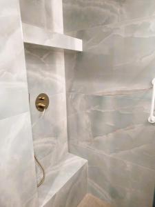 La salle de bains est pourvue d'une douche et de murs en marbre blanc. dans l'établissement Frank and Jimmy apartments, à Tríkala