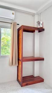 a wooden shelf on a wall with a window at Book Lanta House in Ban Ru Yai