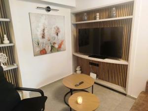 un salon avec une télévision à écran plat et une table dans l'établissement Frank and Jimmy apartments, à Tríkala