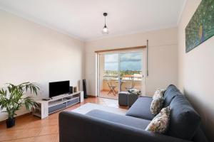 een woonkamer met een bank en een televisie bij Tamara's Apartment in Armação de Pêra