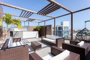 a patio with chairs and a couch on a roof at Season Smart Flats by BLU stay in Porto De Galinhas