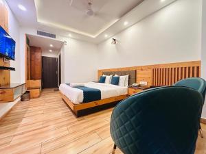 a bedroom with a bed and a tv and chairs at Pine Rock Hotel in Mussoorie Peaceful Stay in Mussoorie