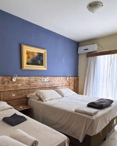 two beds in a bedroom with a blue wall at Pousada Vila Verde in Porto Belo