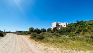 a dirt road with a building on a hill at Cape Holly Beach House in Pringle Bay