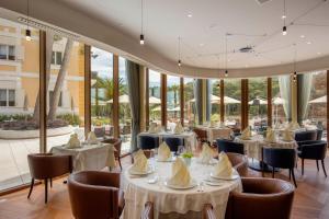 a restaurant with white tables and chairs and windows at Boutique Hotel Alhambra in Mali Lošinj