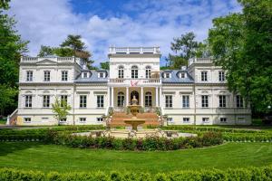 a large white mansion with a fountain in the yard at Pałac Chojnata in Wola Chojnata
