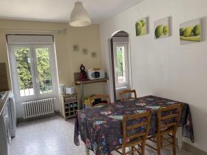 a dining room with a table and two windows at Cosy Er Lann Gîte Séquoïa in Val Couesnon