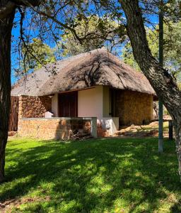 a stone house with a thatched roof in a park at Ilanga Lodge Welgevonden Game Reserve in Welgevonden Game Reserve