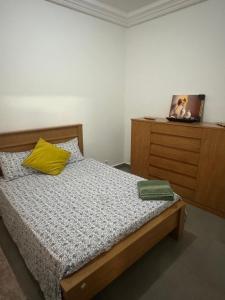 a bedroom with a bed with a yellow pillow and a dresser at Keur Ébène - Appartement Cosy à Ouakam Batrain in Dakar +7 photos