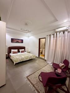 a bedroom with a bed and two chairs at Keur Ébène - Appartement Cosy à Ouakam Batrain in Dakar