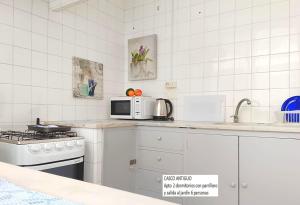 cocina blanca con fogones y microondas en Senda Marina Aparto Hotel, en Punta del Este