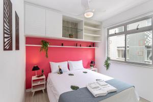 una camera con un letto e una parete con accento rosso di Confortável e bem localizado a 300m da praia a CFB