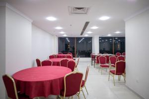 una stanza piena di tavoli e sedie con tovaglia rossa di فندق أكاليل a Al Masfalah