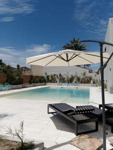een zwembad met een parasol, ligstoelen en een tafel bij Hotel Marciala in Villa Carlos Paz