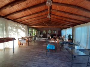 a living room with a wooden ceiling and tables and chairs at Cabañas en monte autóctono con pileta in San Marcos Sierras