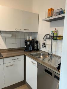 a kitchen with white cabinets and a sink at Alpenblick - Zentralgelegene 2-Zimmer-Wohnung in Kiefersfelden +9 photos
