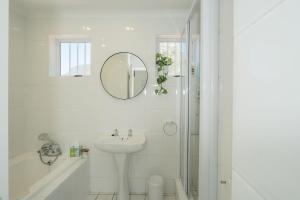 a white bathroom with a sink and a mirror at Ocean Villa Views Fish Hoek in Glencairn +26 photos