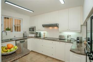 a kitchen with white cabinets and a bowl of fruit at Ocean Villa Views Fish Hoek in Glencairn