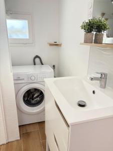 een witte wasruimte met een wasmachine en een wastafel bij L'impasse Japandi in Libourne +3 foto's