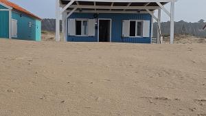 Cabana de Praia no centro de Lisboa في كاباريكا: مبنى أزرق في وسط حقل ترابي